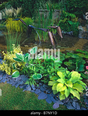 Wildlife pond with Hostas and birds sculptures Stock Photo
