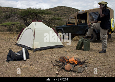A man talking on his satellite phone while on an expedition in his 4x4 vehicle Masailand Kenya Stock Photo