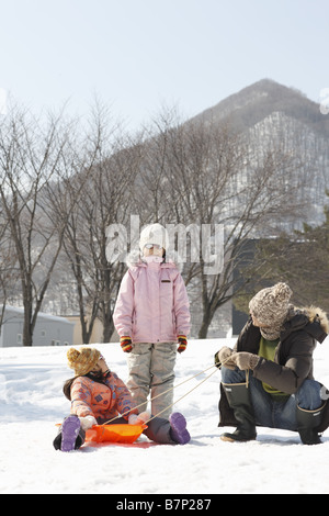 Father and children at play sledding