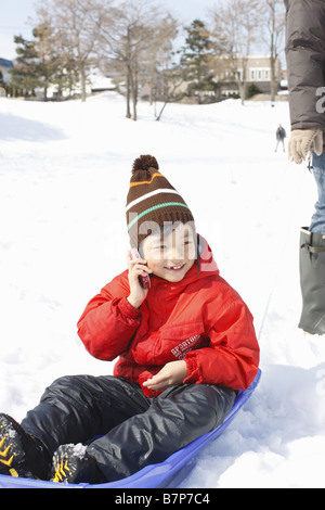 A boy using mobile phone on the sled Stock Photo