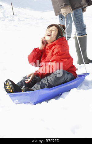 A boy using mobile phone on the sled Stock Photo