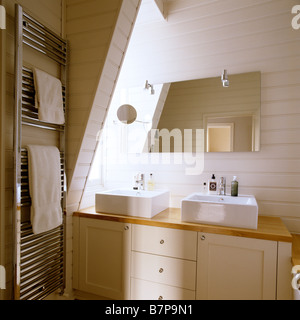 Modern wood panelled bathroom with double basin and metallic towel rail. Stock Photo