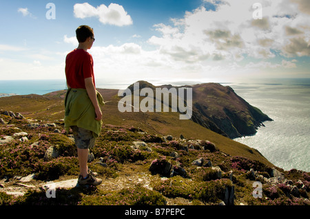 Unidentifiable young caucasian male wearing shorts and t shirt looking out towards the Irish sea at Holyhead on the Isle of Anglesey. Wales Stock Photo