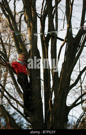 Young teenage girl hanging tibetan buddhist prayer flags on tree top Stock Photo