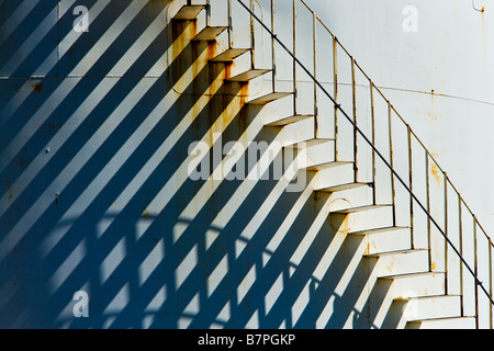 Spiral staircase leading upward, metal abandoned fuel tank. Stock Photo