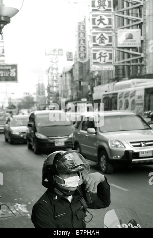 Traffic control policeman wearing a face mask against pollution - Thanon Yaowarat road in Chinatown Bangkok Thailand Stock Photo