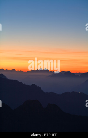 Julian Alps seen from Mangrt in Slovenia dark mountains to foreground with rich orange sunset to horizon and above Stock Photo