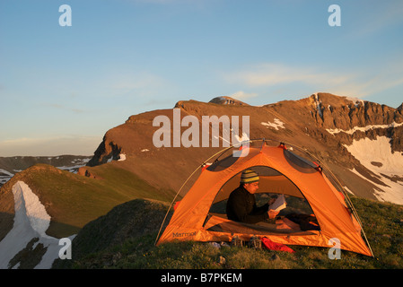 a hiker reading in his tent at sunset high up in the san juan mountains near telluride colorado Stock Photo