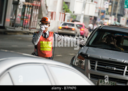 Parking attendant directing heavy traffic Pathumwan district in central Bangkok Thailand Stock Photo