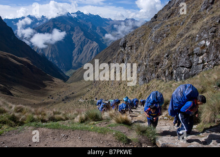 A group of porters carry the equipment required to support Western tour groups on the Inca Trail in Peru. Stock Photo