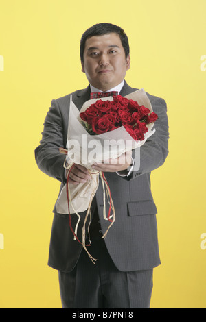 A man in suit holding a bouquet Stock Photo