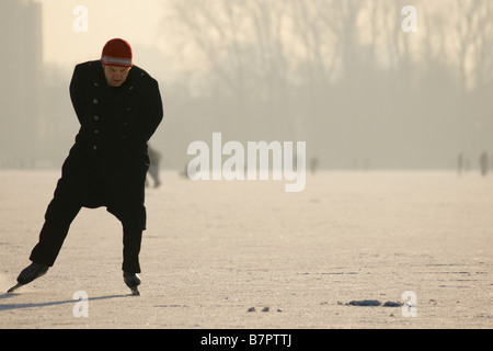 Man in black coat skating on ice surface frozen Kralingse lake winter Netherlands Rotterdam Stock Photo