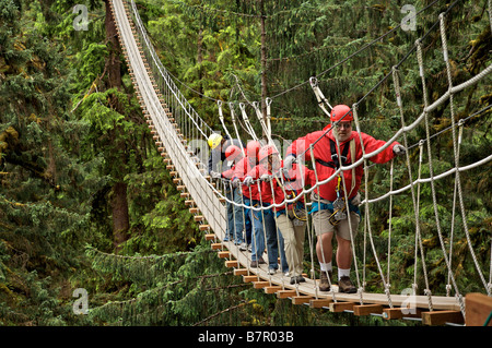 Visitors walk on a suspension bridge in the Alaska Rainforest Sanctuary near Ketchikan, Alaska Stock Photo