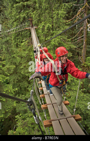 Visitors walk on a suspension bridge in the Alaska Rainforest Sanctuary near Ketchikan, Alaska Stock Photo