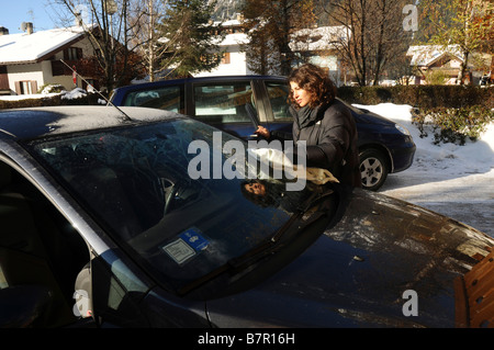 Italy The Dolomites Woman scraping ice off her car s windshield on a cold and frosty morning Model Release Available Stock Photo