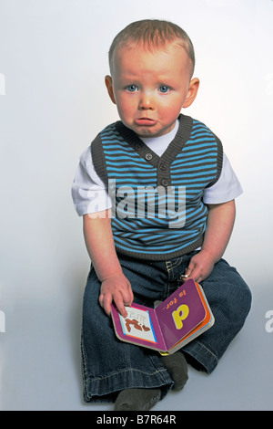 Unhappy boy reading alphabet book Stock Photo