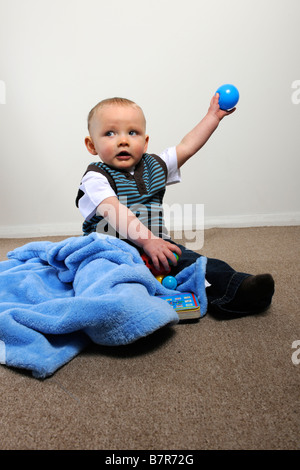 One year old boy with blue ball in outstretched arm Stock Photo