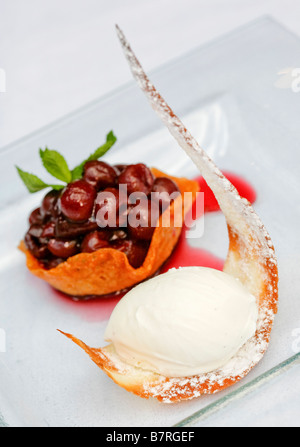 cherrys in a brandy basket with cherry coulis and vanilla ice cream Stock Photo