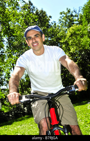 Happy middle aged man riding a bicycle in summer part Stock Photo