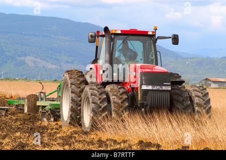 A Case tractor pulling a disk ripper begins the field work in the spring in Skagit County, Washington Stock Photo