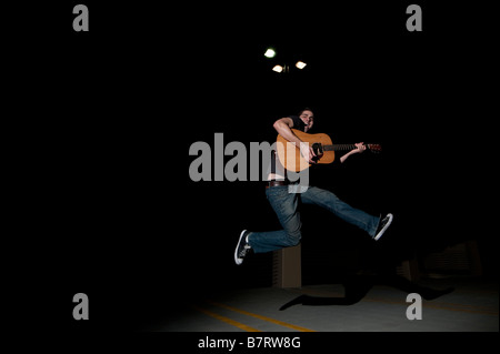 Young man playing guitar jumping Stock Photo