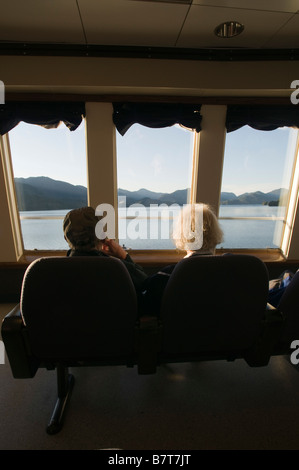 Tourists looking out the window of the observation deck of the Alaska Marine Highway along the Inside Passage Southeast Alaska Stock Photo