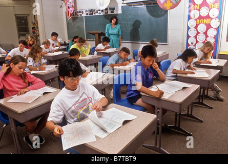 Junior high school students take standardized achievement test in classroom as teacher supervises Stock Photo