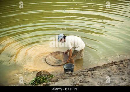 A Laotian man panning for gold in a backwater of the Mekong river. Laos, South East Asia Stock Photo