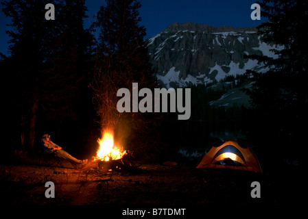 a man sits at a campsite at night in front of a campfire at alta lakes, colorado Stock Photo