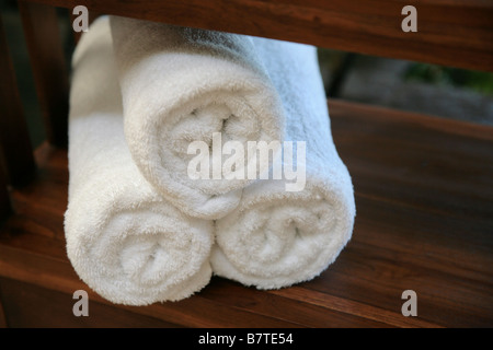 White towels rolled and stacked on a wooden table. Stock Photo