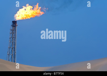A flare stack burning off excess gas at an oil refinery in the desert Stock Photo