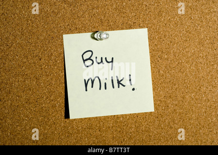 Post it note or memo on a cork board that says buy milk. Stock Photo