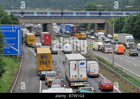 M25 motorway traffic jams & gridlock behind accident being cleared from carriageway with passenger train on railway bridge Brentwood Essex England UK Stock Photo