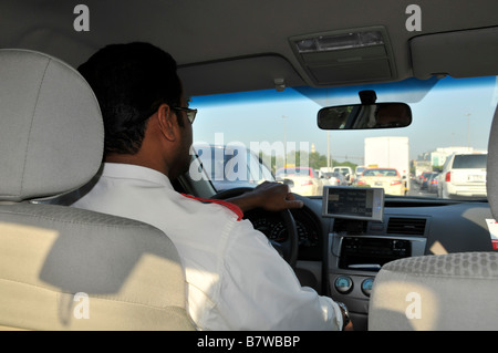 Interior close up back view Dubai taxi cab worker driver hand on steering wheel driving along busy road stuck in traffic jam United Arab Emirates UAE Stock Photo