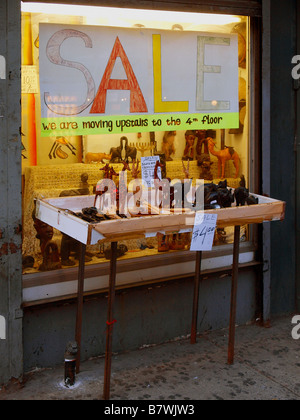 Little animal statuettes and figures on sale on a rickety display table in front of a hand-drawn window sign in New York City. Stock Photo