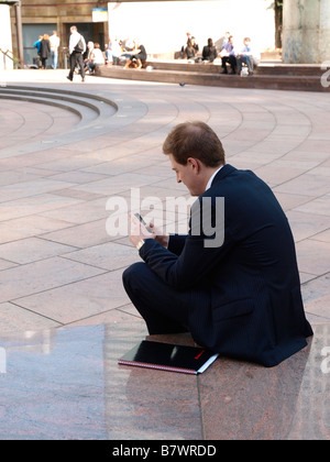 Businessman using a mobile phone near Canary Wharf in Docklands London Stock Photo