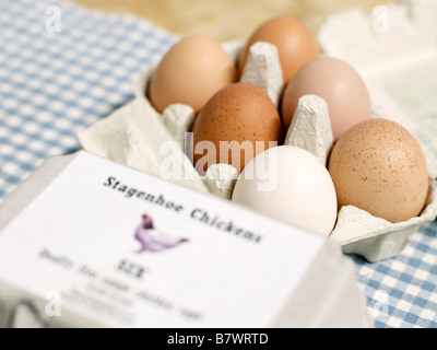 Mixture of different coloured organic eggs in a box sat on a gingham place mat Stock Photo