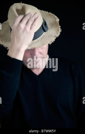 A portrait of a mature man wearing an old straw hat. Stock Photo