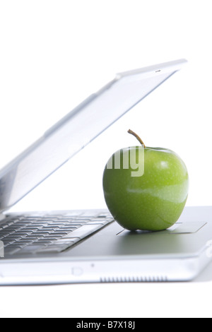 A green apple sitting on a laptop isolated Stock Photo