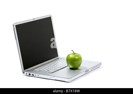 A green apple sitting on a laptop isolated Stock Photo