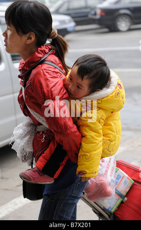 Chinese migrant woman carrying her baby on her back at the train station of Nanchang, Jiangxi province, China. 05-Feb-2009 Stock Photo