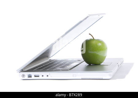 A green apple sitting on a laptop isolated Stock Photo