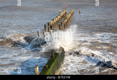 Waves crash against wooden groyne Coastal defences Lowestoft Suffolk England Stock Photo