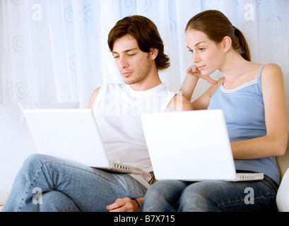 Man and woman using laptop on sofa smiling Stock Photo