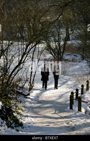 Couple walking on snow covered Hampstead Heath, London, England. Stock Photo