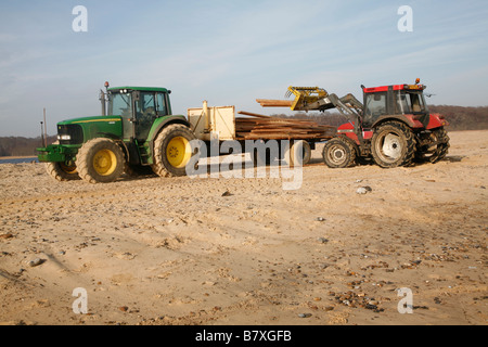 Tractor carrying salvaged timber washed up of beach from stricken cargo ship Suffolk England January 2009 Stock Photo