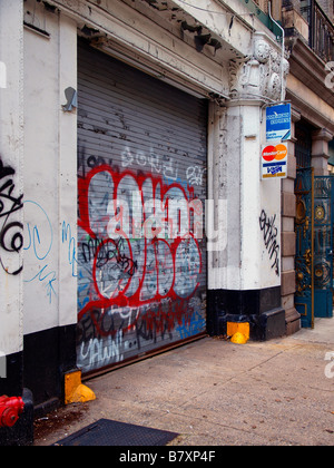 Major credit card logos on a sign affixed to a concrete column beside a steel security door covered in graffiti. Stock Photo