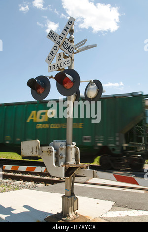 ILLINOIS DeKalb Railroad crossing gate down and signal flashing freight train moving on railroad tracks Stock Photo