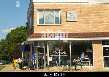ILLINOIS Sycamore Man wash windows of cafe restaurant in small town customers inside street sign and neon sign Stock Photo