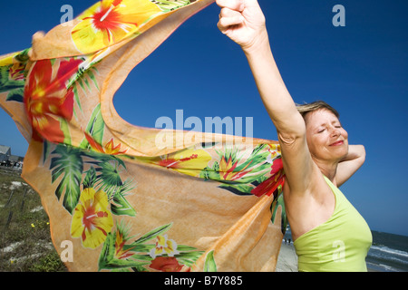 woman holding scarf in the wind at beach Stock Photo